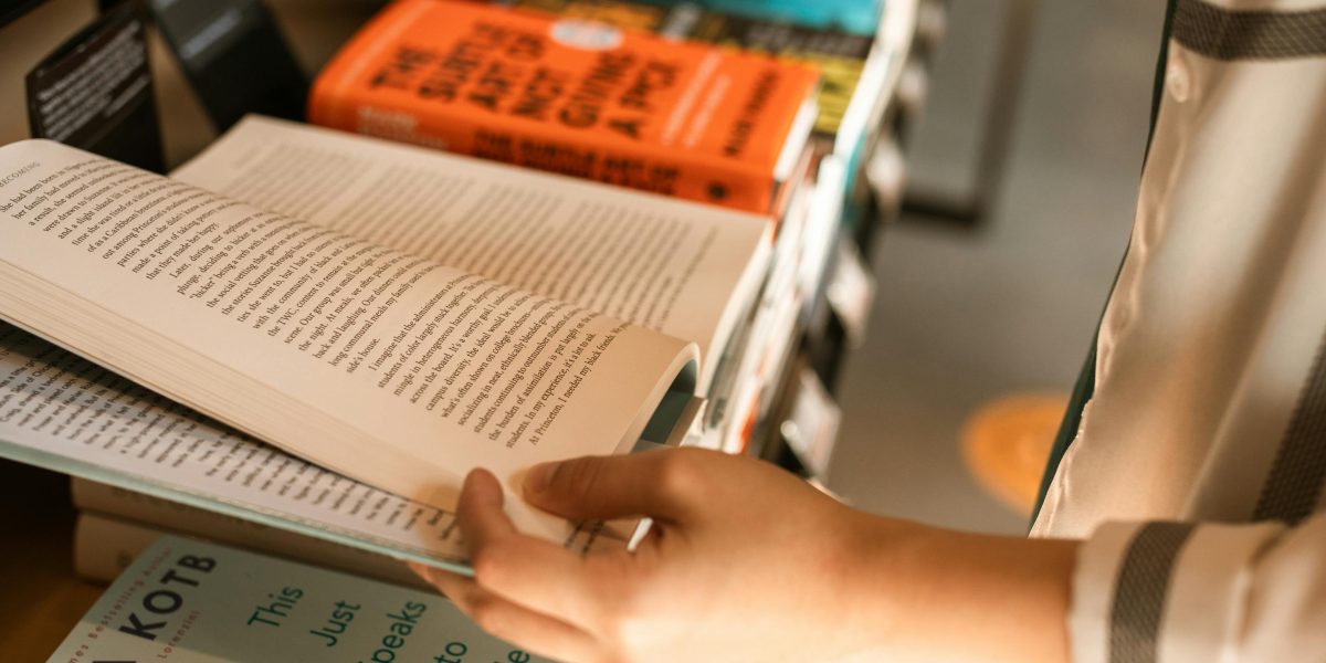 A person browsing various titles, deciding which book to read next at a bookstore.