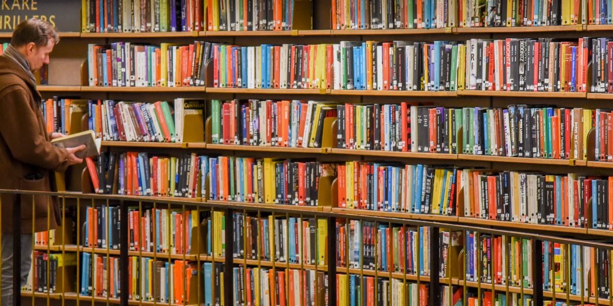 A person browsing a bookshelf or library, thoughtfully considering their next read, symbolizing the search for a new captivating story.