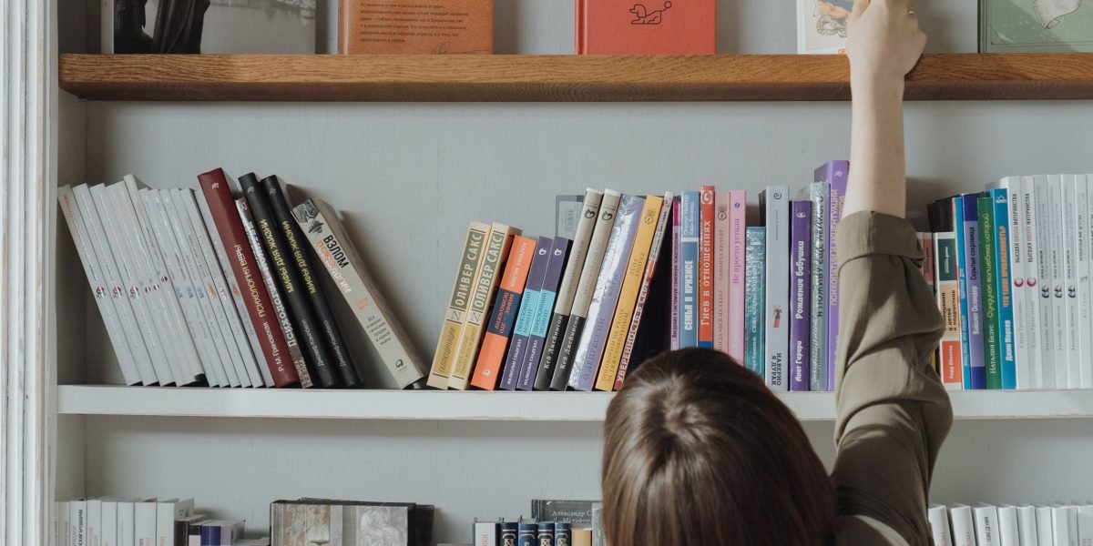 A person in a bookstore or library, making a confident choice from a selection of books.
